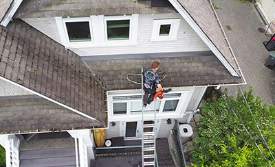 our employee cleaning gutters from a ladder